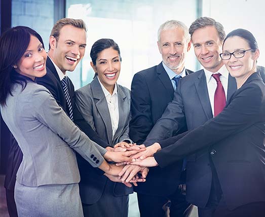 group of smiling professionals stacking their hands in a show of teamwork
